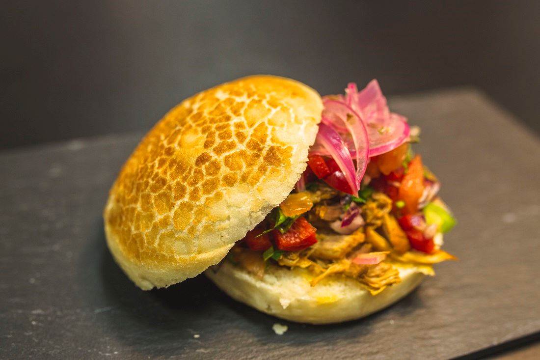 Hamburguesa Tigre con cochinita pibil, pico de gallo y cebolla encurtida